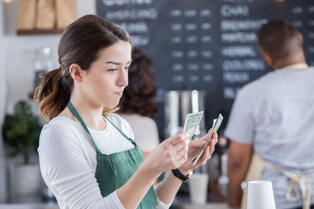 Young female barista has a disappointed expression on her face as she counts her tips at the end of the day.
 (Getty Images/SDI Productions)