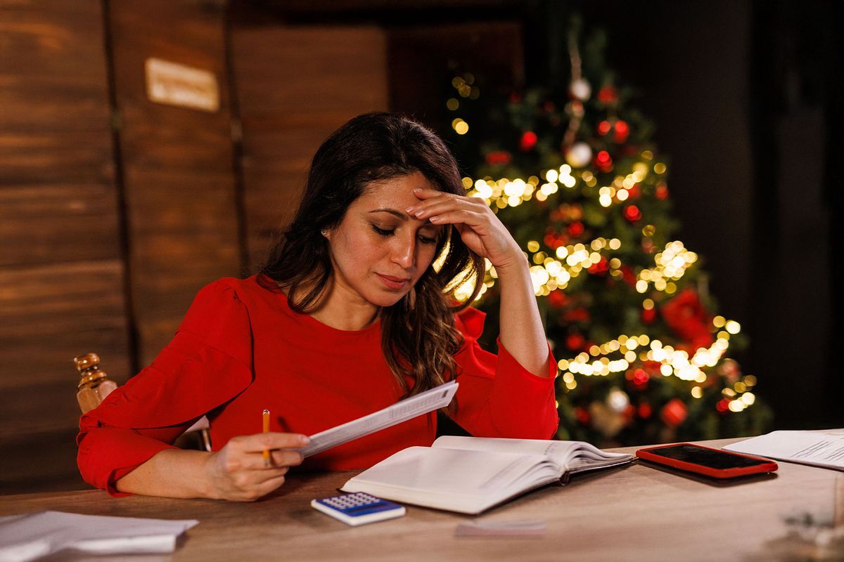 Adult woman sitting at her desk, head in hand, sorting out receipts, finances and bills during Christmas holidays (Getty Images/fotostorm)