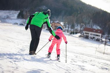 Father Helping Daughter To Learn Skiing