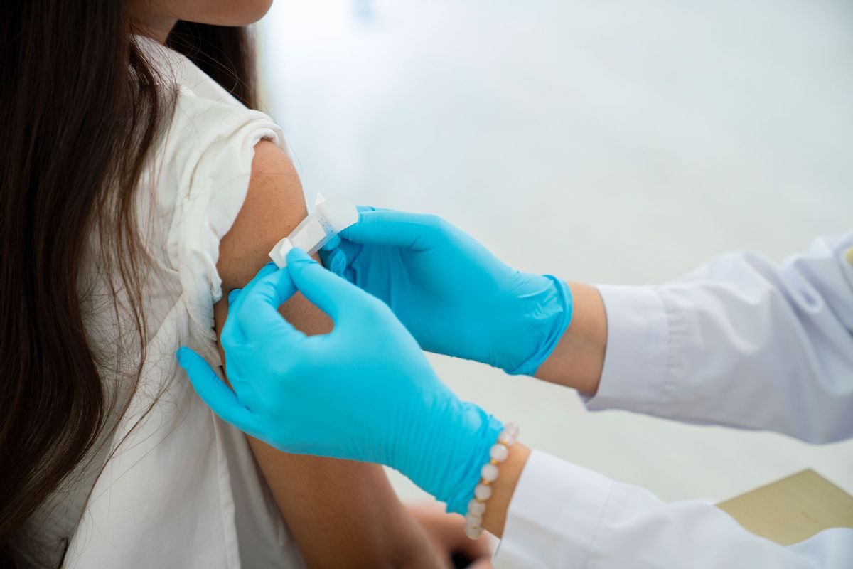 Doctor applies bandage to preteen girl's arm following an immunization (Getty Images/Witthaya Prasongsin)