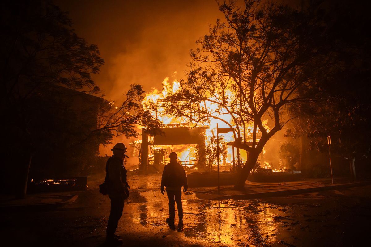 Firefighters watch the flames from the Palisades Fire burning a home during a powerful windstorm on January 8, 2025 in the Pacific Palisades neighborhood of Los Angeles, California. (Apu Gomes/Getty Images)