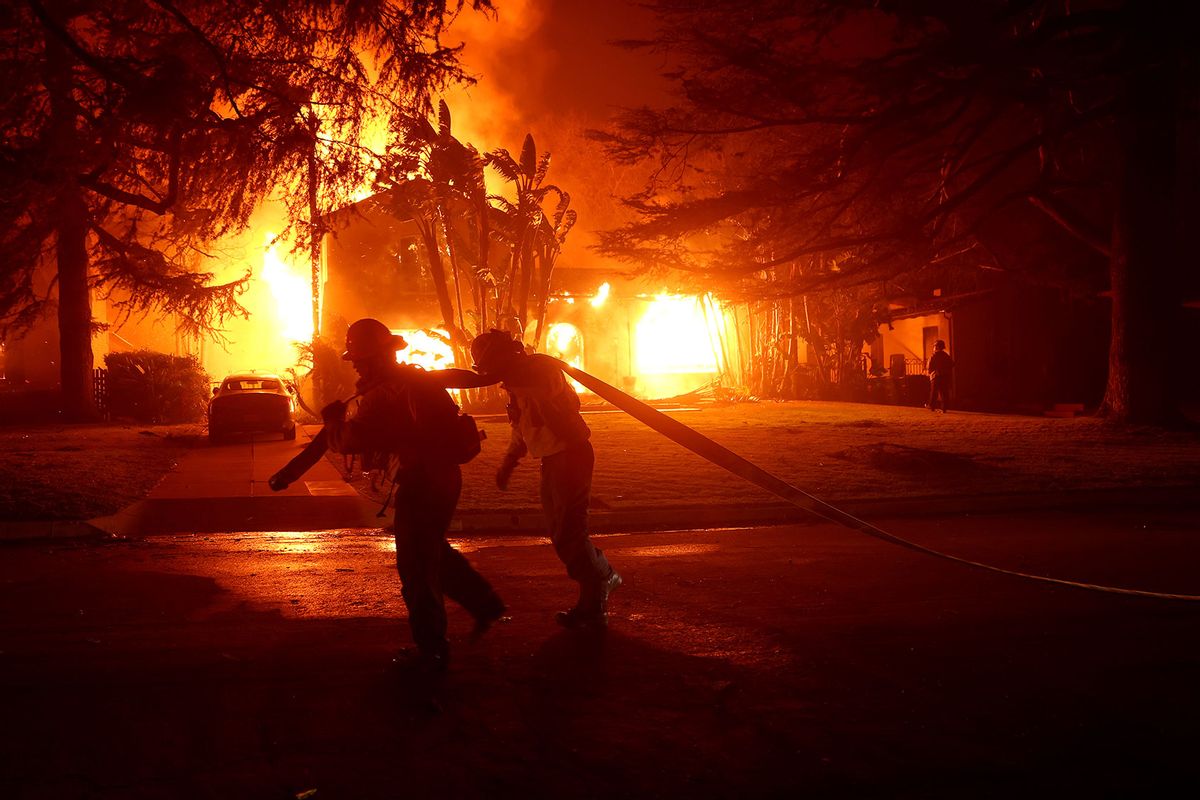 Los Angeles County firefighters pull a hose in front of a burning home as the Eaton Fire moved through the area on January 08, 2025 in Altadena, California. (Justin Sullivan/Getty Images)