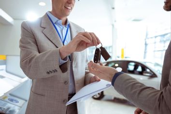 Man receiving car key of his new car in car dealership