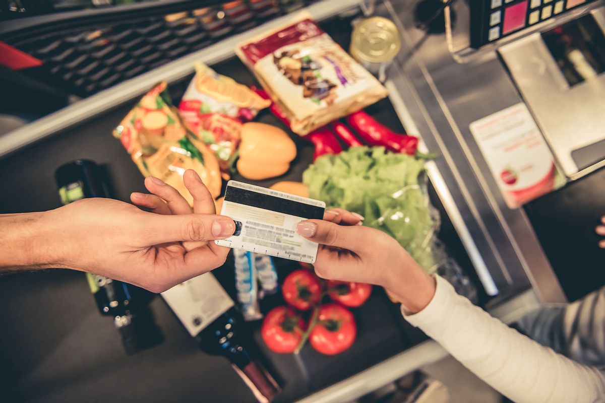 Customer handing over their credit card at the supermarket checkout (Getty Images/GeorgeRudy)