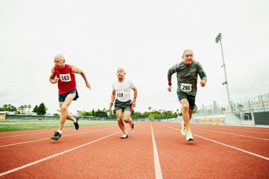 Senior male track athletes running sprint on track during race