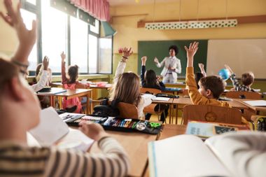 students raising their hands teacher class elementary school