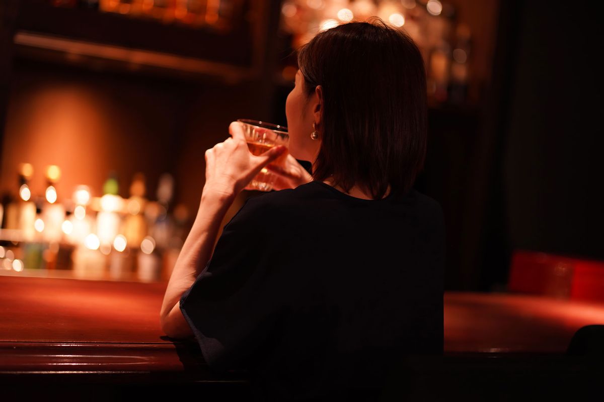 Woman drinking alone at a bar (Getty Images/yamasan)