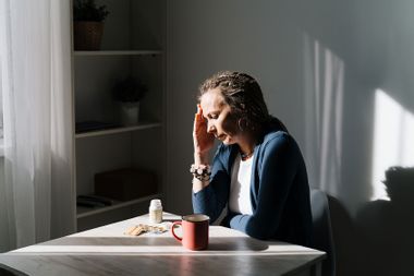 woman sitting at table head in her hand