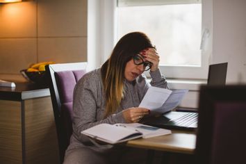 Woman worried looking at her bills paperwork