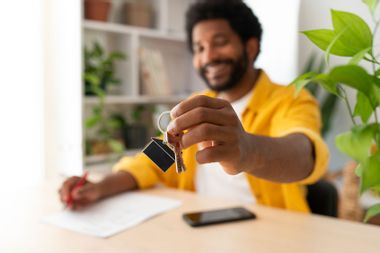 Young man holding keys after buying new house